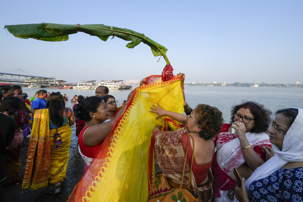 Hindu devotees perform rituals around a banana wrapped in a sari on the first day of Durga Puja festival on the banks of the Hooghly River in Kolkata, India, Saturday, Oct. 21, 2023. The five-day festival commemorates the slaying of a demon king by goddess Durga, marking the triumph of good over evil. (AP Photo/Bikas Das)