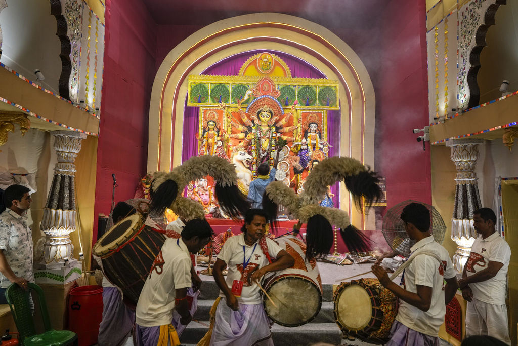 A Hindu priest worship the Hindu goddess Durga as Indian drummers beats the drum on the first day of Durga Puja festival in Kolkata, India, Saturday, Oct. 21, 2023. The five-day festival commemorates the slaying of a demon king by goddess Durga, marking the triumph of good over evil. (AP Photo/Bikas Das)
