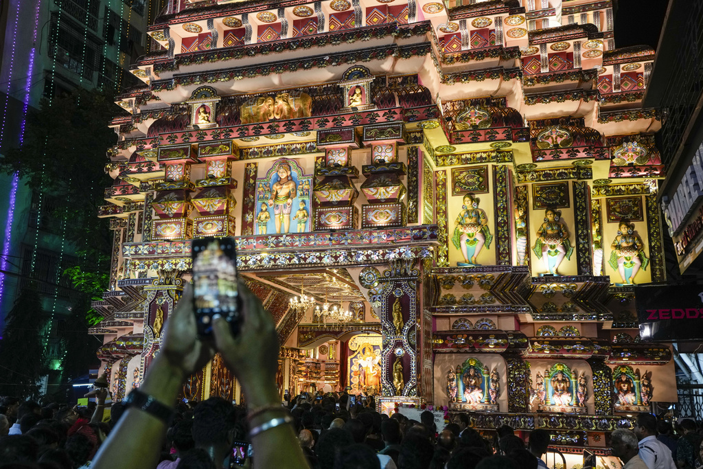 A man takes a photo of the facade of a temporary worship venue of Hindu goddess Durga on the first day of Durga Puja festival in Kolkata, India, Saturday, Oct. 21, 2023. The five-day festival commemorates the slaying of a demon king by goddess Durga, marking the triumph of good over evil. (AP Photo/Bikas Das)
