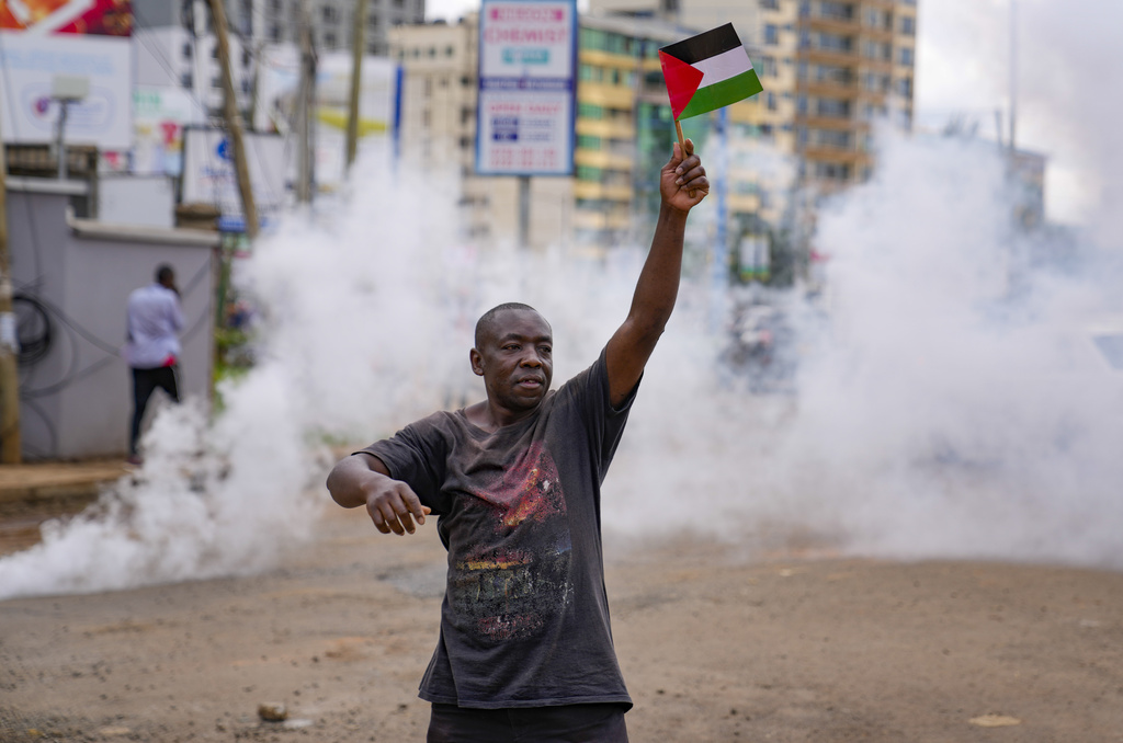 A demonstrator waves a Palestinian flag as Kenyan police officers fire teargas canisters during a protest against Israel and in support of Palestinians, in Nairobi, Kenya, Thursday, Nov. 9, 2023. (AP Photo/Brian Inganga)