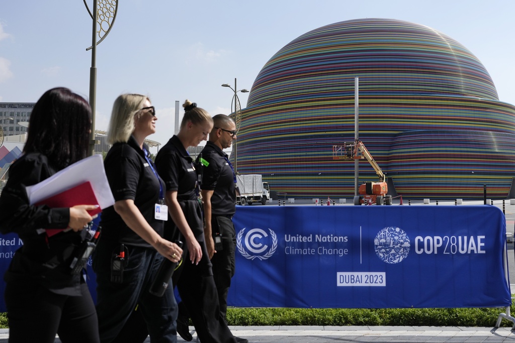 People walk near a logo for the COP28 U.N. Climate Summit, Wednesday, Nov. 29, 2023, in Dubai, United Arab Emirates. (AP Photo/Rafiq Maqbool)