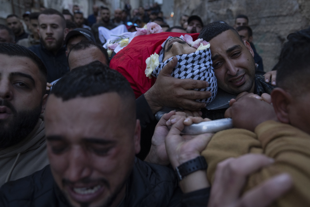Palestinian mourners carry the body of Ali Alqam, 32, during his funeral in the West Bank refugee camp of Qalandia, south of Ramallah, Monday, Dec. 4, 2023. The Palestinian health ministry said Alqam was killed during an Israeli army raid in Qalandia on Monday morning. (AP Photo/Nasser Nasser)