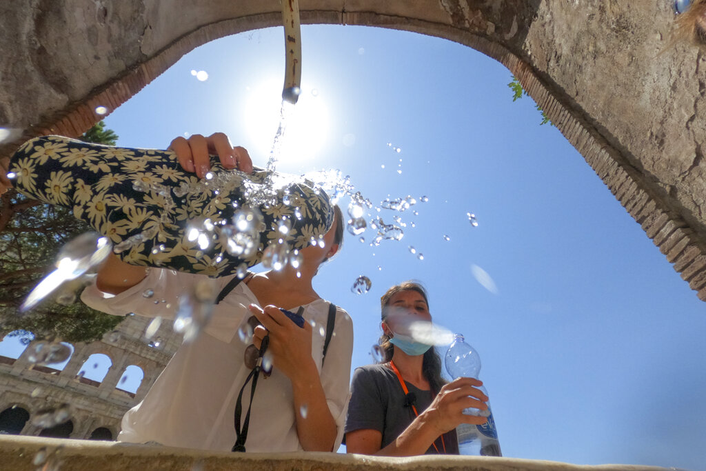 People refresh at a fountain next to the Colosseum, in Rome, Thursday, Aug. 12, 2021. In Italy, 15 cities received warnings from the health ministry about high temperatures and humidity with peaks predicted for Friday. The cities included Rome, Florence and Palermo, but also Bolzano, which is usually a refreshing hot-weather escape in the Alps, (AP Photo/Andrew Medichini)