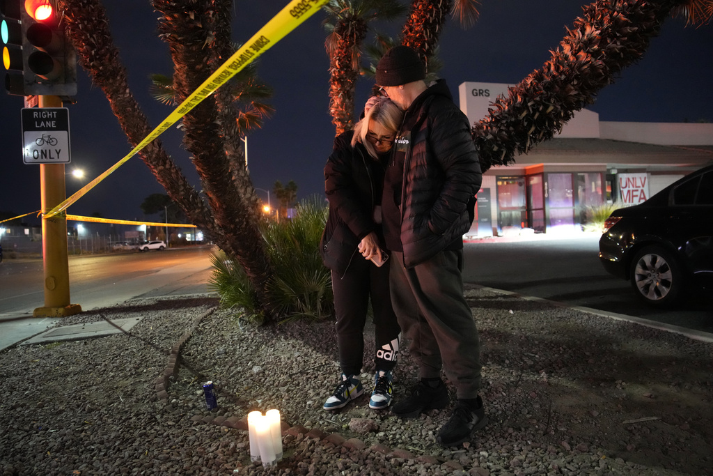 Sean Hathcock, right, kisses Michelle Ashley after the two left candles for victims of a shooting at the University of Nevada, Las Vegas, Wednesday, Dec. 6, 2023, in Las Vegas. The two graduated from the school and live nearby. (AP Photo/John Locher)