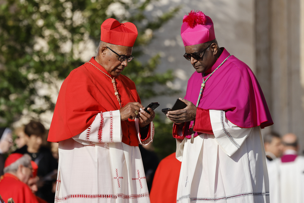 FILE - A cardinal, left, and a bishop check their smartphone in St. Peter's Square at The Vatican, Saturday, Sept. 30, 2023, as they wait for a consistory where Pope Francis will create 21 new cardinals to start. Pope Francis called Thursday for an international treaty to ensure artificial intelligence is developed and used ethically, arguing that the risks of technology lacking human values of compassion, mercy, morality and forgiveness are too great. (AP Photo/Riccardo De Luca, File)