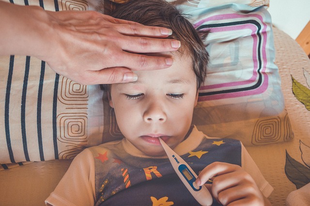 Bambino con la febbre misura la temperatura col termometro. Foto di Victoria da Pixabay.