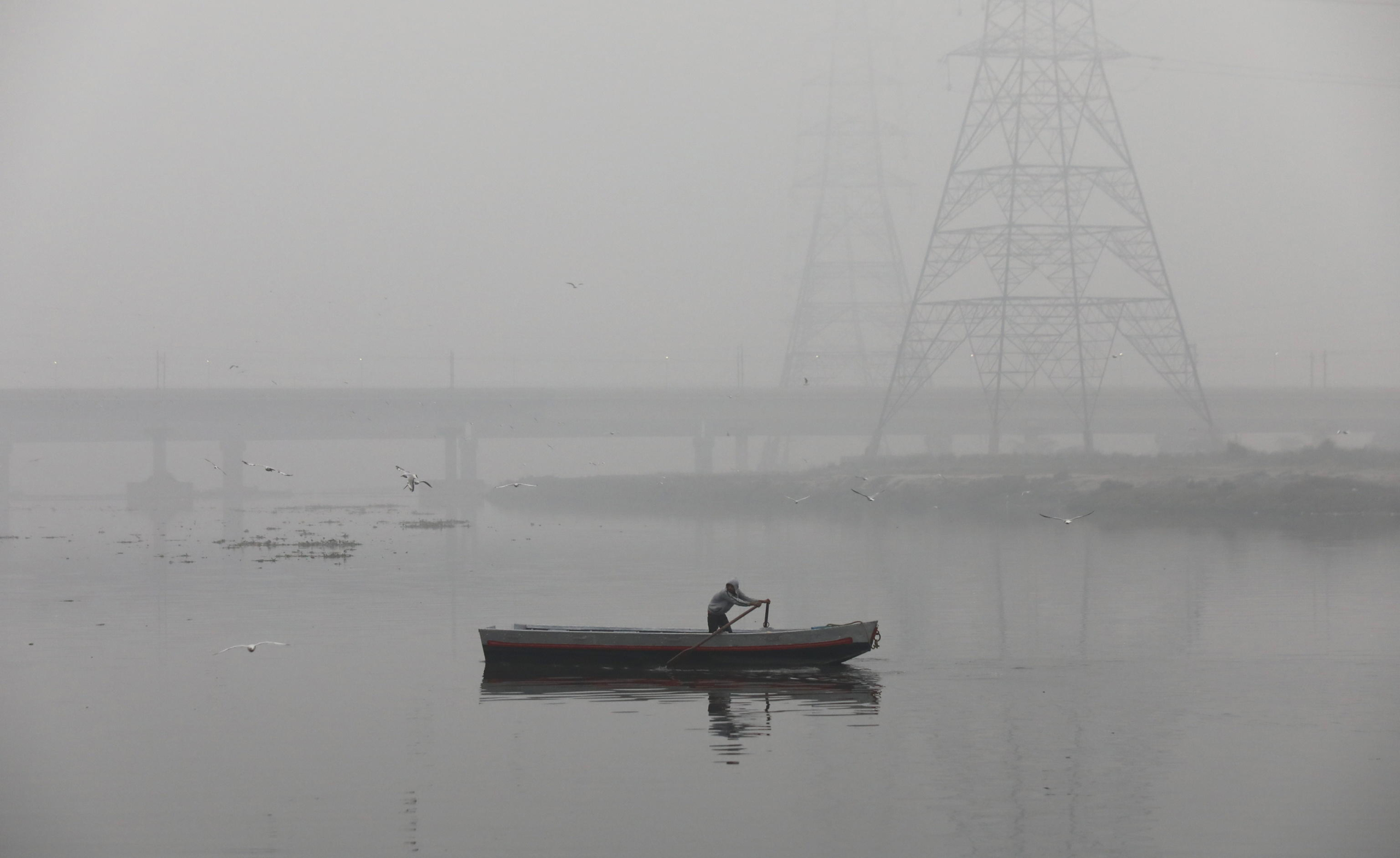 epa11058145 A Indian man rows a boat on a foggy, cold winter morning on the banks of the Yamuna river in New Delhi, India, 05 January 2024. Winter takes a heavy toll each year around northern India, as poverty forces many homeless people to live outdoors. Temperatures in the northern Indian regions continue to decrease. Migratory birds, including seagulls, arrive at Delhis Yamuna bank during the onset of winter season as they migrate through Delhi making a temporary home in Yamuna river and sometime fed by devotees who arrive to bathe in the river in the morning time.  EPA/RAJAT GUPTA