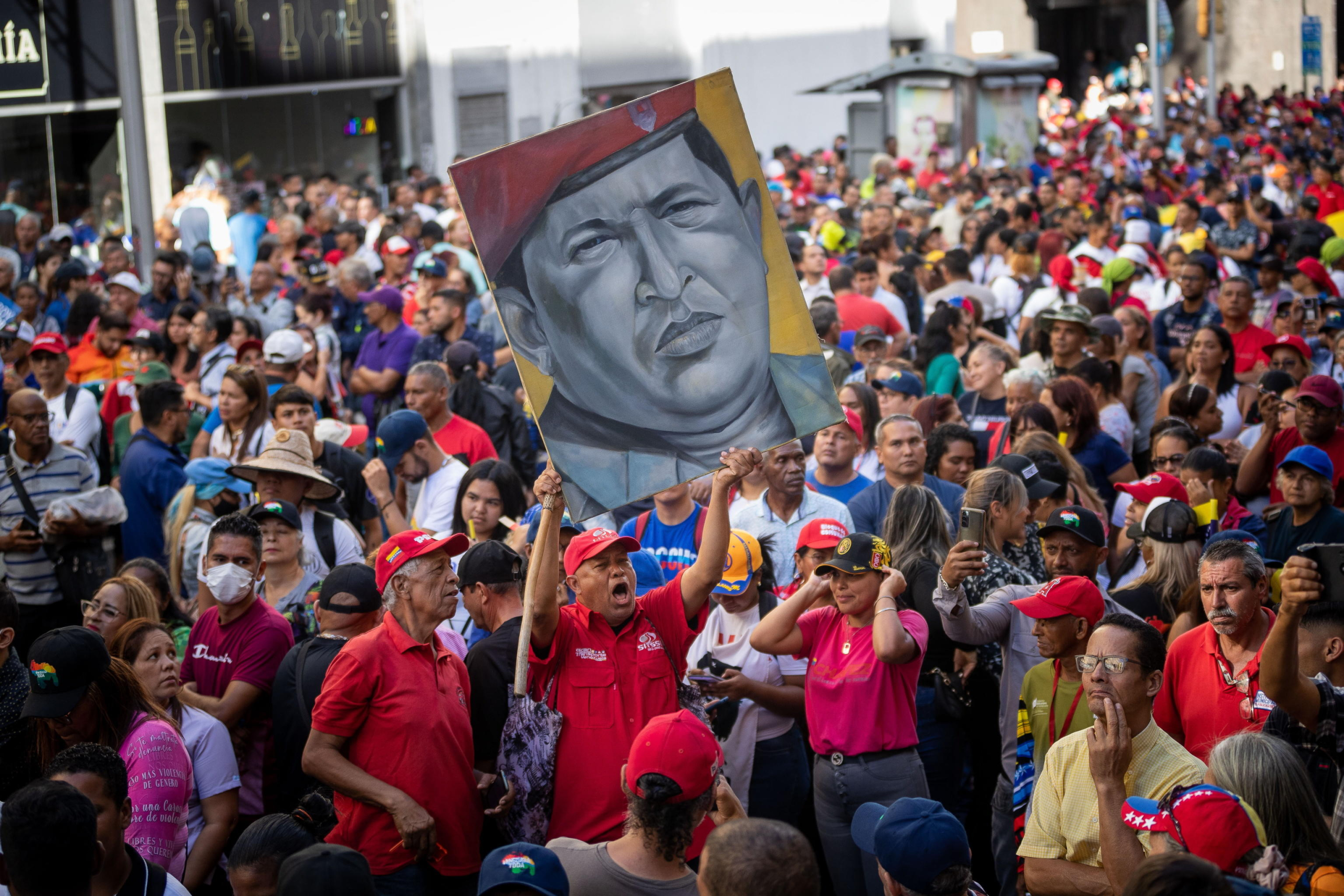 epa11099830 A man carries a picture with the image of the late former president Hugo Chavez during a march in favor of the government of Nicolas Maduro in Caracas, Venezuela, 23 January 2024. Maduro assured that he will continue to govern the country 