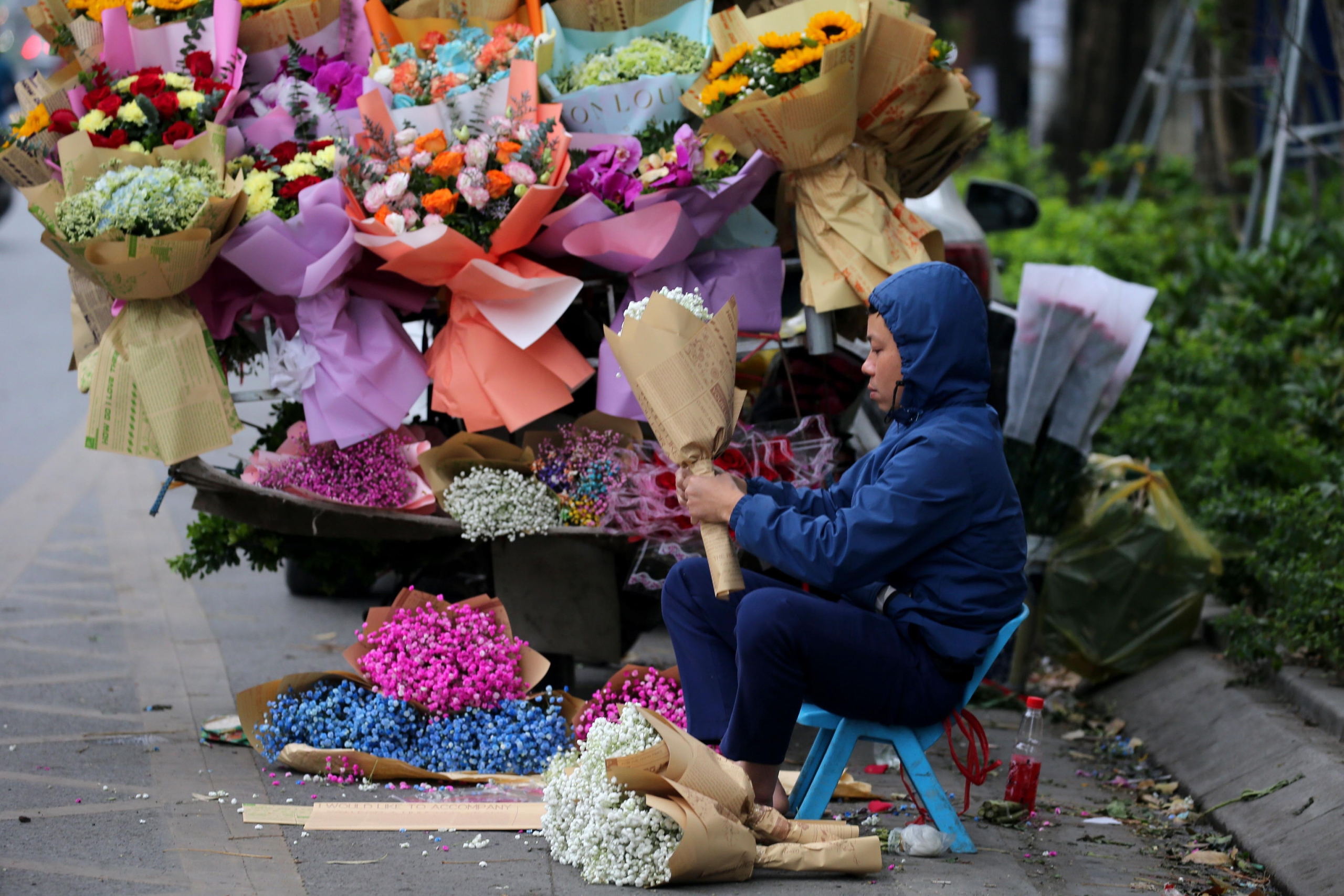 epa11205700 A florist person makes a bouquet on a street in Hanoi, Vietnam, 08 March 2024. International Women's Day in Vietnam is marked annually on 08 March and men usually give flowers and gifts to female relatives and friends.  EPA/LUONG THAI LINH