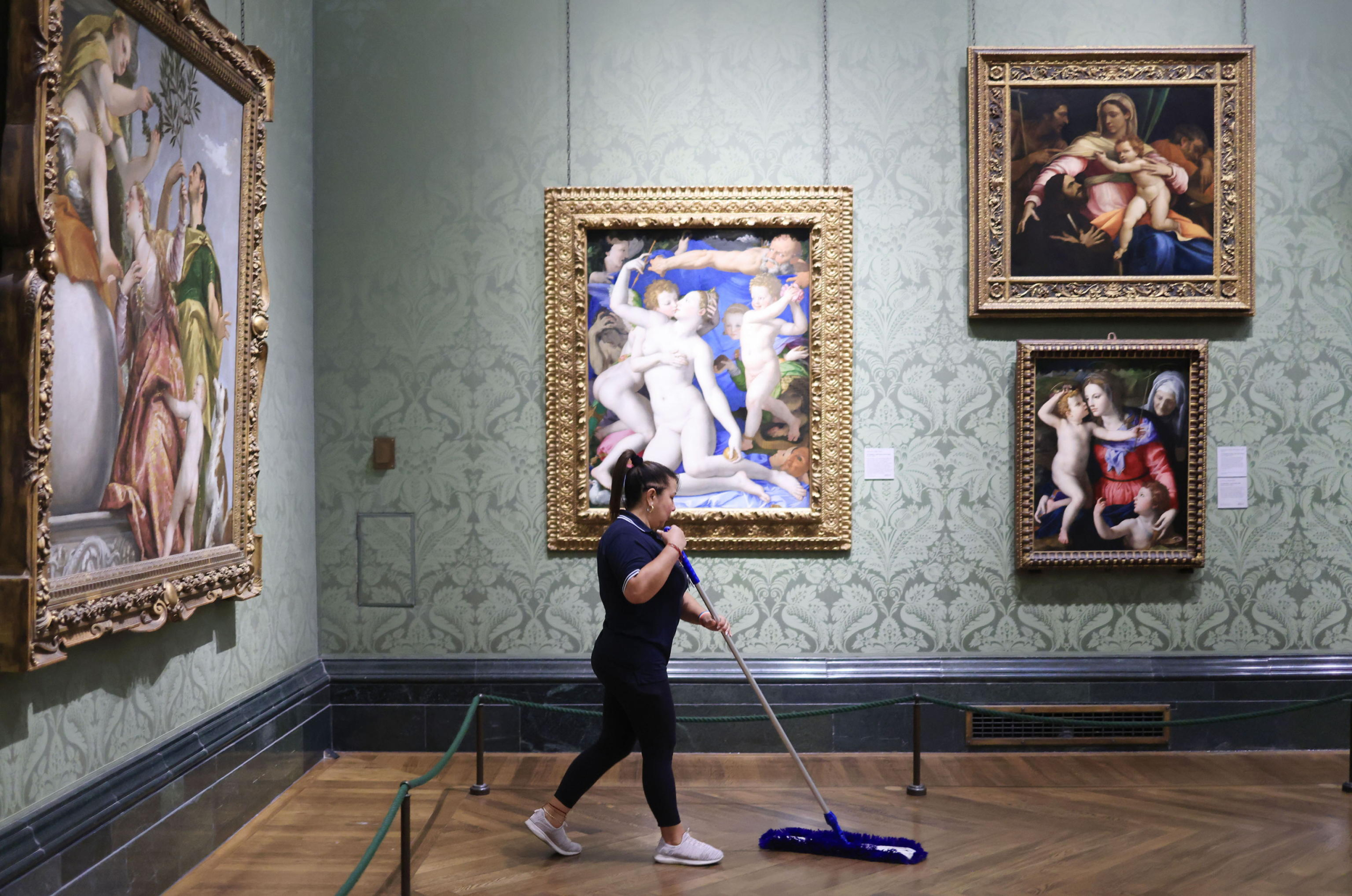 epa11328621 A cleaner sweeps under the painting 'An Allegory with Venus and Cupid' by Bronzino in the National Gallery in London, Britain, 08 May 2024 (issued 09 May 2024). On 10 May 2024 the National Gallery celebrates its Bicentenary. The National Gallery was established in 1824 with the first 38 paintings donated by banker John Julius Angerstein. The collection was initially displayed in a townhouse at 100 Pall Mall. After this became too small,  a new building was completed on Trafalgar Square in 1838 designed by the architect William Wilkins. The art collection currently comprises 2,300 works, spanning the major traditions of Western European painting with works by Van Gogh, Caravaggio, Turner, Constable, Michelangelo, Velazquez and Rembrandt. The National Gallery building welcomed over three million visitors in 2023,  which is open 361 days a year, free of charge. The National Gallery will mark the bicentenary year with 12 months of events celebrating art and creativity across the UK.  EPA/NEIL HALL  ATTENTION: This Image is part of a PHOTO SET