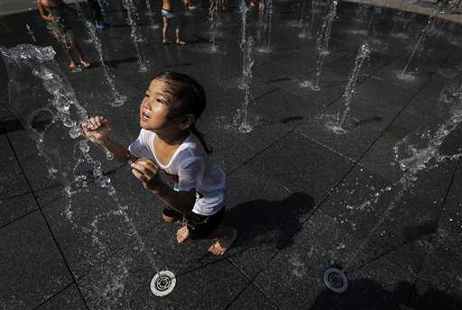 Bambina gioca con l'acqua per rinfrescarsi in Giappone