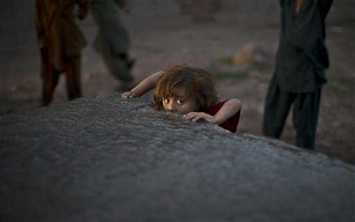 Bambino afgano beve acqua in Pakistan