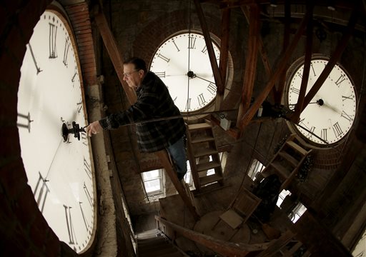 un orologiaio modifica le lancette per l'ora legale