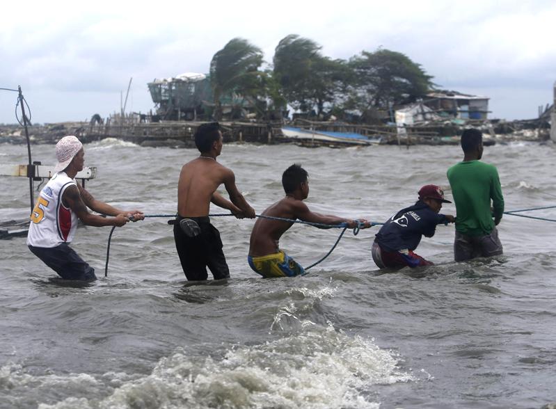 Pescatori filippini tirano le barche a riva in attesa dell'arrivo del tifone al nord di Manila