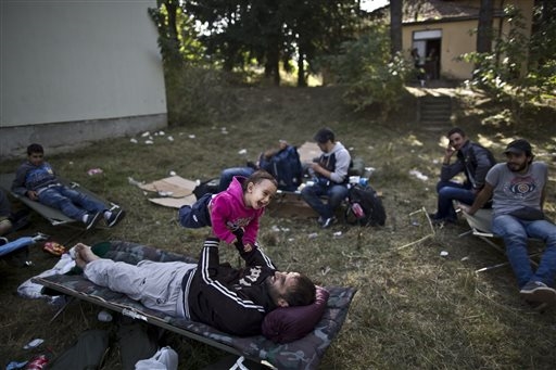 Un rifugiato siriano gioca con la figlia sul prato dove sono accampati in Croazia al confine con l'Ungheria