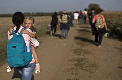 Una donna porta in braccio la figlia nel lungo cammino dalla Serbia alla Croazia