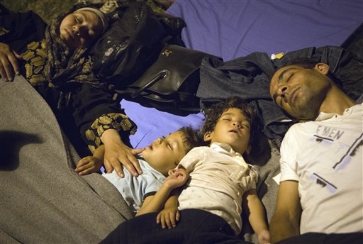 Una famiglia di migranti riposa per terra durante il viaggio verso la Croazia