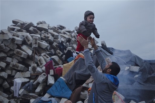 Un papà prende in braccio il figlio nel campo profughi di Idomeni