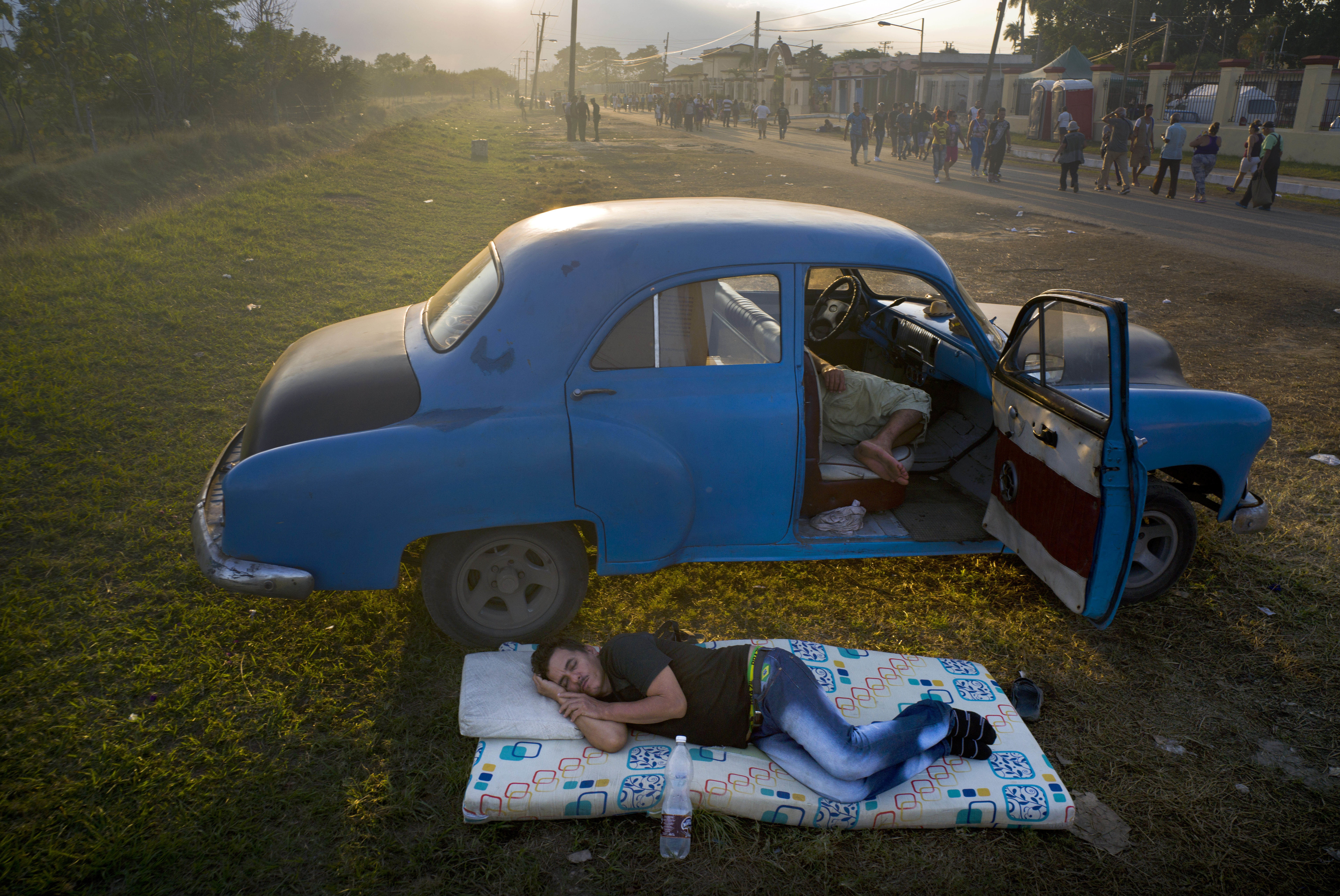 Men rest while waiting for a Mass in honor of the Catholic Saint Lazarus, to be held at the church in El Rincon, an area of Santiago de las Vegas, Cuba, as the sun sets Friday, Dec. 16, 2016. Saturday marks the second year since the start of negotiations between Cuba and U.S. to restore diplomatic ties. Saint Lazarus' feast day is every Dec. 17. (AP Photo/Ramon Espinosa)