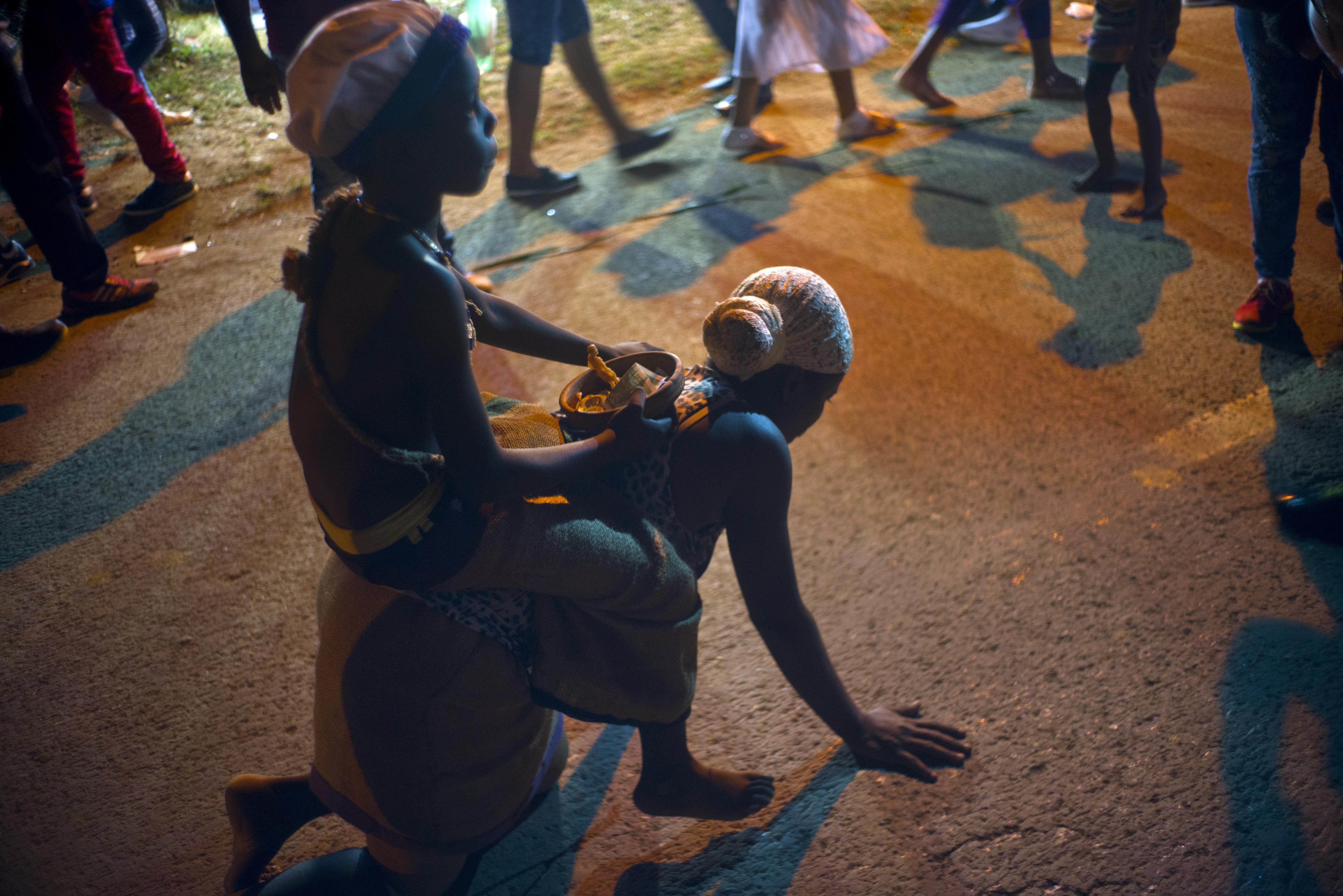A child rides on the back of a believer in Saint Lazarus walking on her knees as a self-imposed penance during her pilgrimage to the saint's shrine in El Rincon, an area of Santiago de las Vegas, Cuba, late Friday, Dec. 16, 2016. The Catholic saint is also known as the Afro-Cuban Yoruba deity Babalu Aye, protector of the sick, an example of Cuba's religions syncretism. His feast day is every Dec. 17. (AP Photo/Ramon Espinosa)