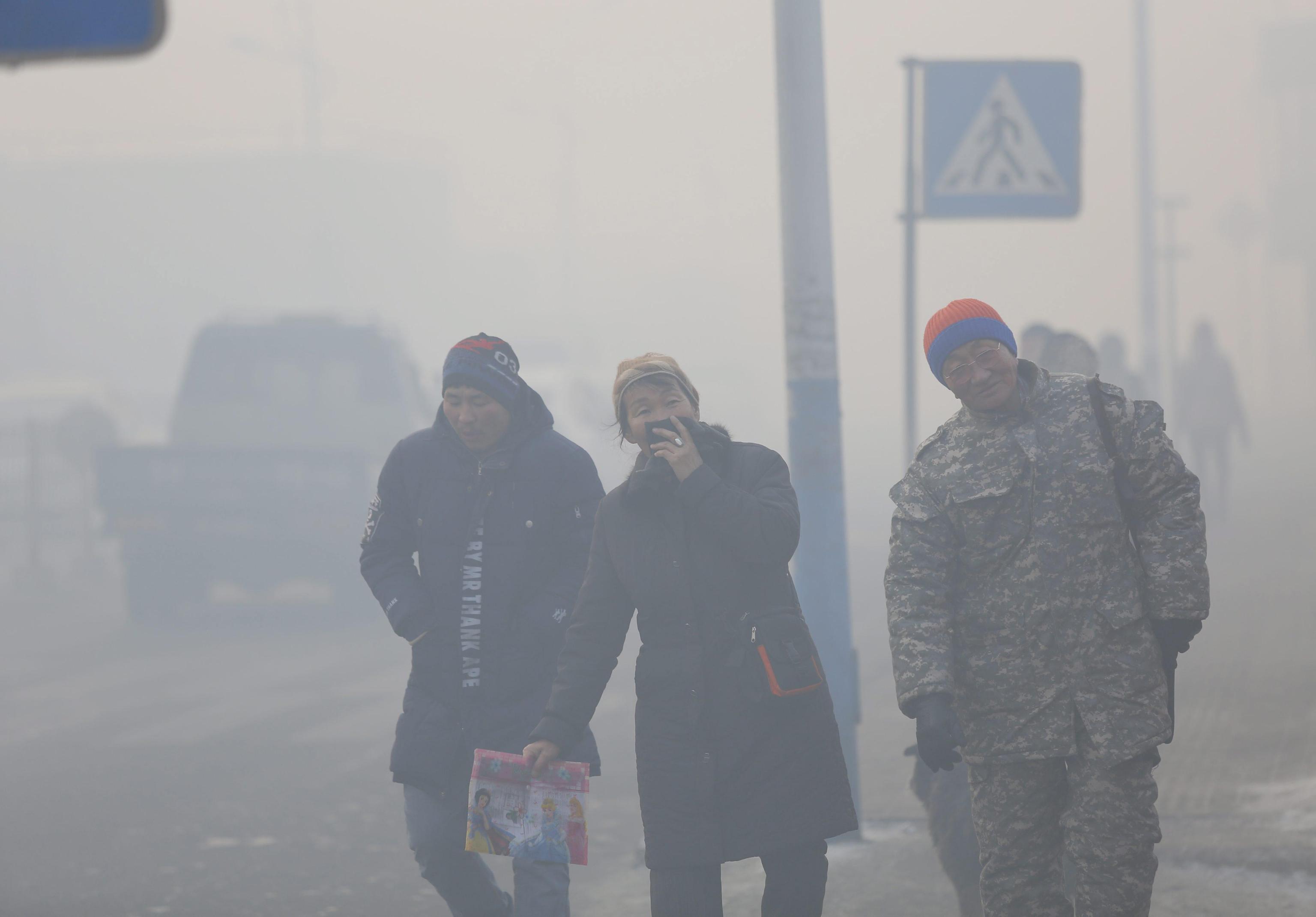 epa05712041 Mongolians wearing masks walk along a road shrouded in haze in the capital city of Ulaanbaatar, Mongolia, 12 January 2017. Mongolian President Tsakhiagiin Elbegdorj said on 11 January 2017, that air pollution in Ulaanbaatar has reached disaster levels and the city is declared to be in a state of disaster where measures like evacuations are recommended for some areas, according to local media.  EPA/DAVAANYAM DELGERJARGAL