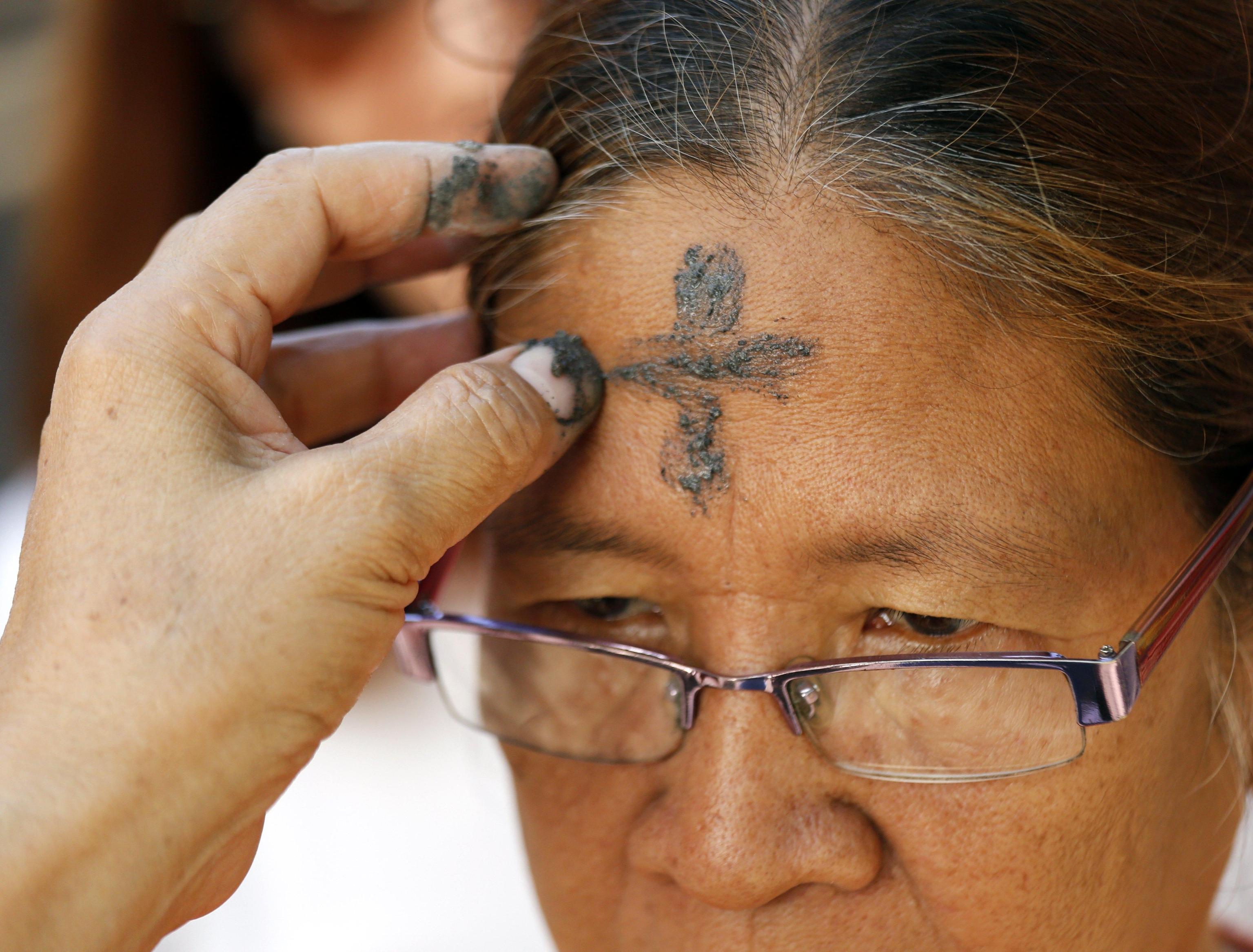 epa05822042 A Filipino devotee receives a black soot on her forehead to observe Ash Wednesday at a Catholic church  in Pasay city, south of Manila, Philippines, 01 March 2017. Filipino Catholic started the 40-day Lenten Season on Ash Wednesday by going to church to have their forehead marked with an ash cross sign. The rite is part of the culture of many Filipino Catholics, symbolizing their acceptance for the start of Lent and to show their sincere efforts and discipline to cleanse their lives of sin through prayers.  EPA/FRANCIS R. MALASIG