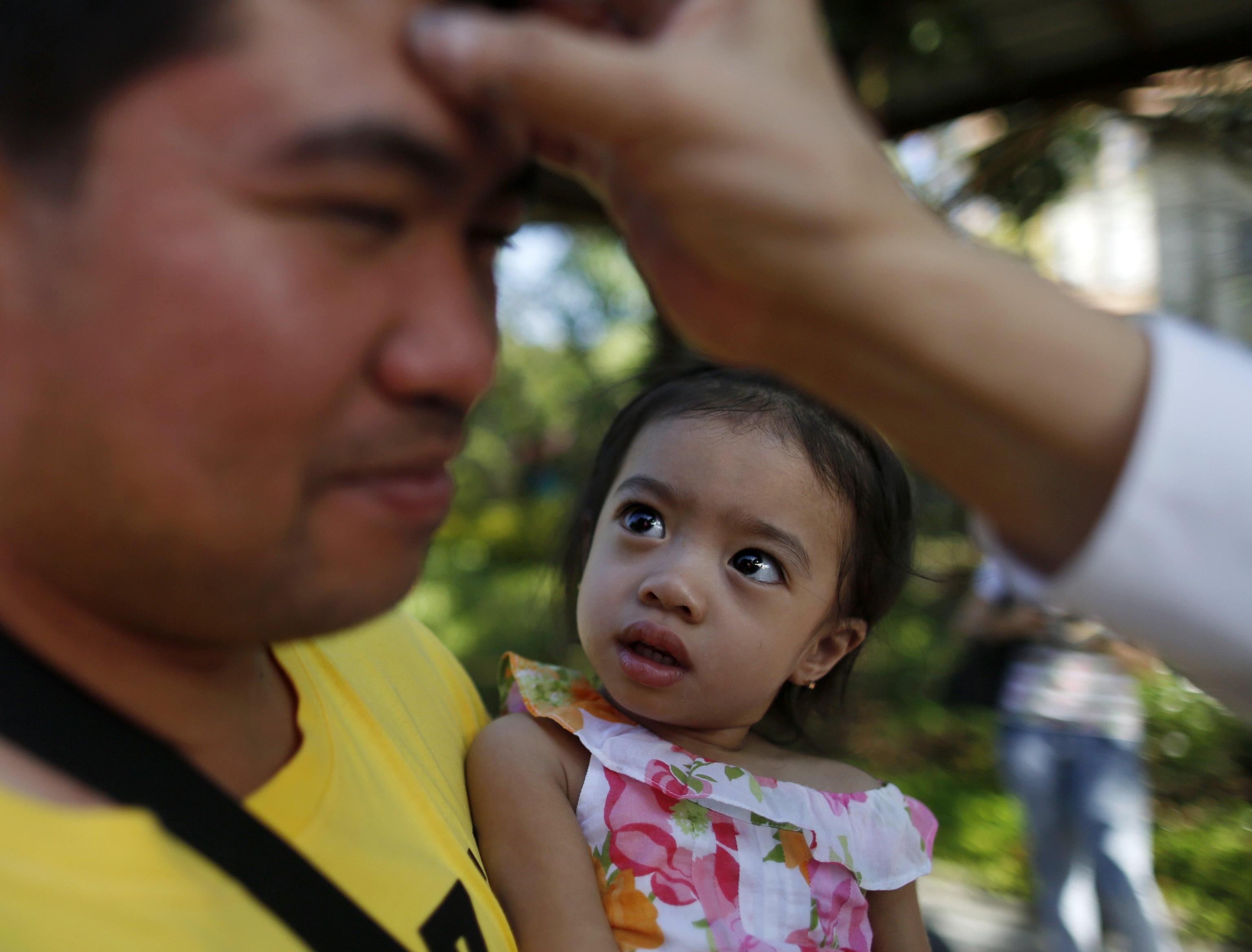 epa05822048 A Filipino child looks on as her father receives a cross marking on the forehead during Ash Wednesday in Pasay city, south of Manila, Philippines, 01 March 2017. Filipino Catholic started the 40-day Lenten Season on Ash Wednesday by going to church to have their forehead marked with an ash cross sign. The rite is part of the culture of many Filipino Catholics, symbolizing their acceptance for the start of Lent and to show their sincere efforts and discipline to cleanse their lives of sin through prayers.  EPA/FRANCIS R. MALASIG
