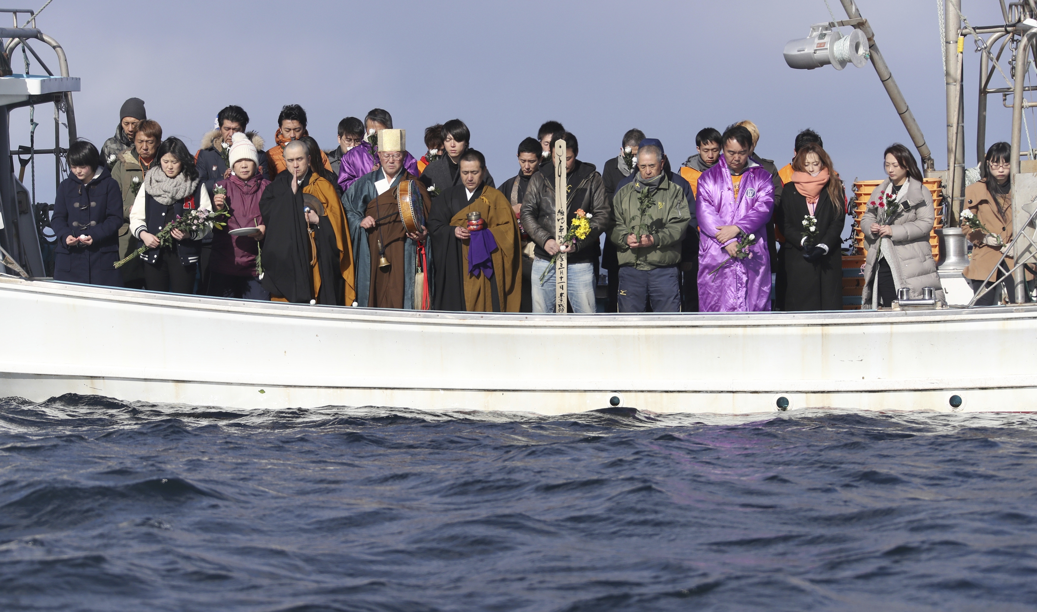 Bereaved family and relatives from a ship offer flowers for the victims on the waters off Utatsu,  Minami-Sanriku town, in  Miyagi Prefecture, on March 11, 2017,  six years after the  magnitude 9.0-earthquake and the powerful  tsunami hit.  ( The Yomiuri Shimbun via AP Images )