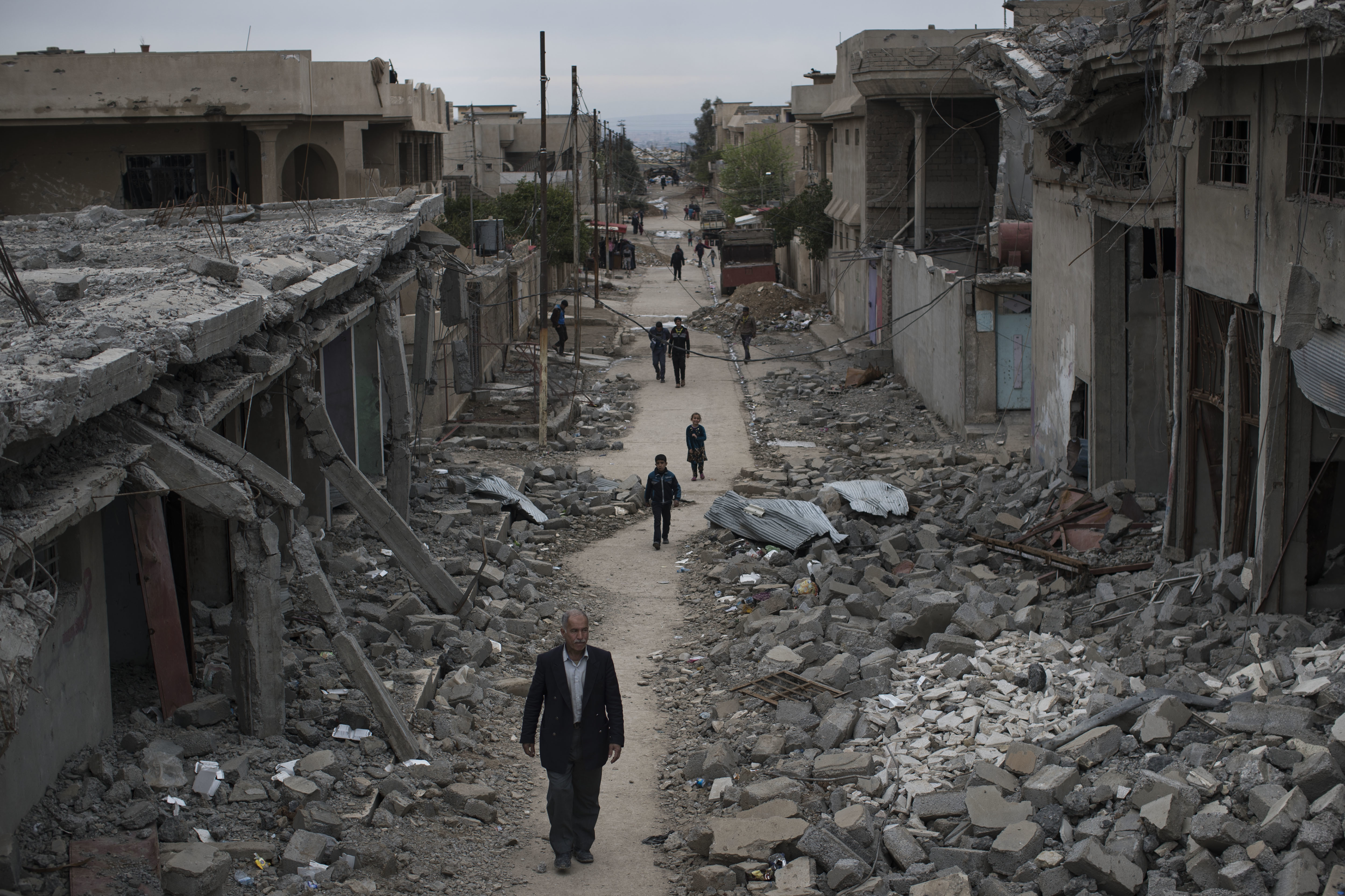 Iraqi civilians walk in a neighborhood recently liberated by Iraqi security forces on the western side of Mosul, Iraq, Wednesday, March 22, 2017. (AP Photo/Felipe Dana)