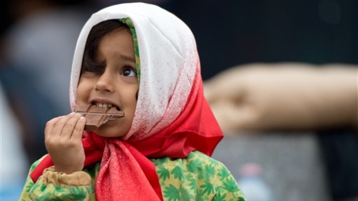 Una bambina siriana riceve cioccolata all'arrivo in Germania. Il Paese accoglie i rifugiati siriani