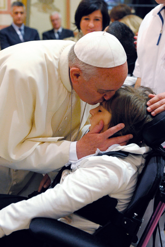 Papa Francesco bacia un bambino disabile durante la visita all'Istituto Serafico di Assisi