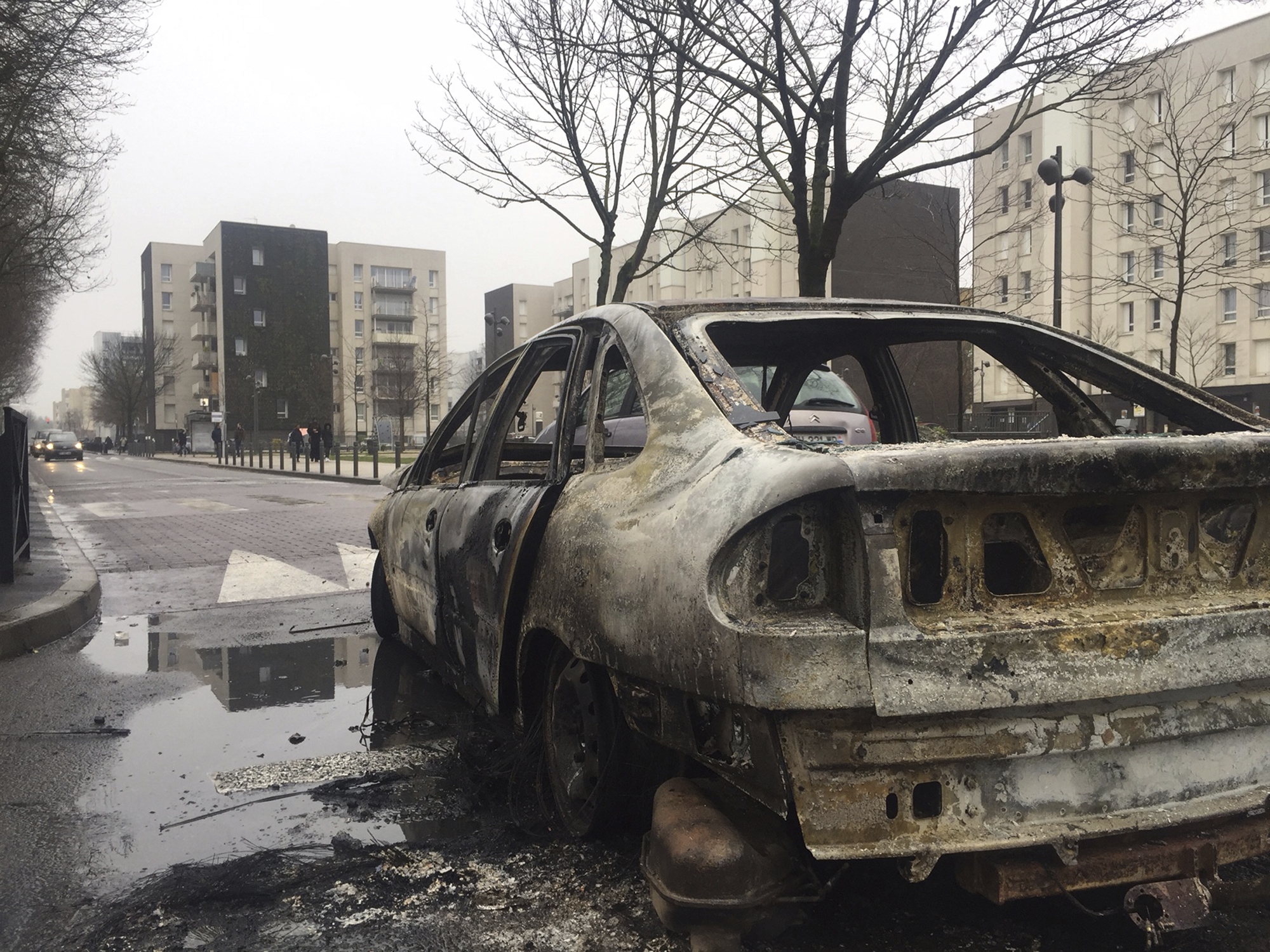Wreckage of a car after it was burnt out by angry protesters on Monday night in support of a young black man who authorities allege was sodomized by a police officer's baton last week during a police operation that targeted drug traffickers, in Aulnay-sous-Bois, north of Paris, France, Tuesday, Feb. 7, 2017. French police have said that 26 protesters were arrested during an eruption of violence against police in the Paris suburbs in which a police car was torched. (AP Photo/Alex Turnbull)