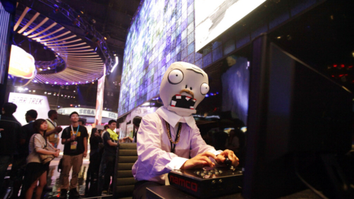 FILE - In this June 5, 2012 file photo, a man dressed as a zombie from Plants vs. Zombies mobile app game plays a video game at the Namco Bandai booth at E3 2012 in Los Angeles. Four years before Activision seeded plans to obtain King Entertainment, rival Electronic Arts made its largest purchase yet with the acquisition of mobile game publisher PopCap Games for $750 million in 2011. The creator of such beloved series as 