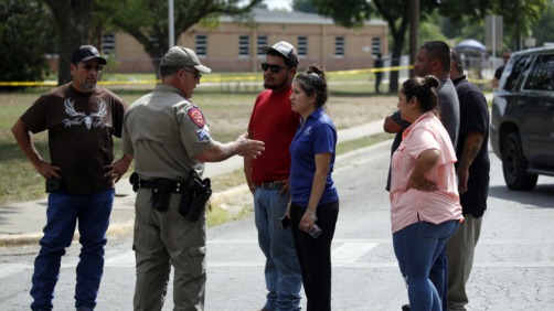 A policeman talks to people asking for information outside of the Robb Elementary School in Uvalde, Texas, Tuesday, May 24, 2022. An 18-year-old gunman opened fire at the Texas elementary school, killing multiple people. Gov. Greg Abbott says the gunman entered the school with a handgun and possibly a rifle. AP Photo/Dario Lopez-Mills)