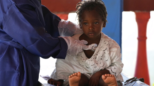 A healthcare worker examines a Haitian migrant child at a tourist campground in Sierra Morena, in the Villa Clara province of Cuba, Wednesday, May 25, 2022. A vessel carrying more than 800 Haitians trying to reach the United States wound up instead on the coast of central Cuba, government news media said Wednesday. (AP Photo Ramon Espinosa)