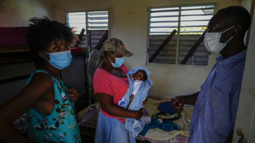 Loverie Horat, left, stands by her mother holding her 24-day-old daughter Maylie Dhavavaise as her husband Maximaud Cherizad looks on, at a campground being used to house the large group of Haitian migrants with whom they are traveling, in Sierra Morena in Cuba's Villa Clara province, Thursday, May 26, 2022. A vessel carrying more than 800 Haitians trying to reach the United States wound up instead on the coast of central Cuba, in what appeared to be the largest group seen yet in a swelling exodus from crisis-stricken Haiti. (AP Photo Ramon Espinosa)