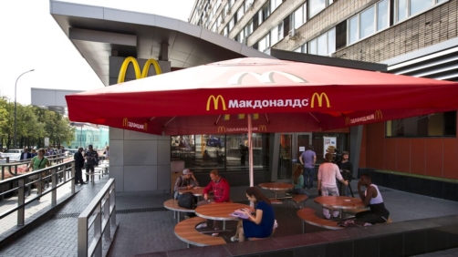 People walk past the oldest Moscow's McDonald's outlet in downtown Moscow, which was opened on Jan. 31, 1990, and is closed on Thursday, Aug. 21, 2014. Russian news agencies reported Thursday that the country's food safety agency will conduct checks on McDonald's restaurants in the Urals following food safety complaints, a day after four branches of the chain were shuttered in Moscow. (AP Photo/Alexander Zemlianichenko)
