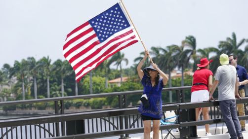 Adriane Shochet stands on a bridge outside the entrance to former President Donald Trump's Mar-a-Lago estate, Tuesday, Aug. 9, 2022, in Palm Beach, Fla. The FBI searched Trump's Mar-a-Lago estate as part of an investigation into whether he took classified records from the White House to his Florida residence, people familiar with the matter said Monday. (AP Photo/Lynne Sladky)
