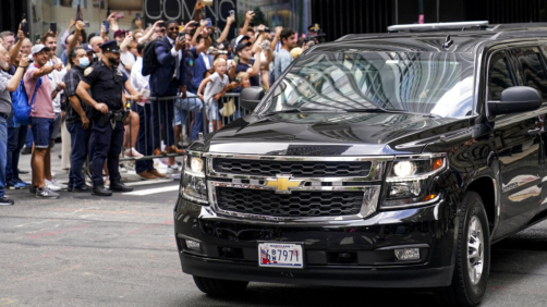 Onlookers reacts as a vehicle carrying former President Donald Trump departs 28 Liberty after depositions in a civil investigation, Wednesday, Aug. 10, 2022, in New York. Trump says he invoked the Fifth Amendment and wouldn't answer questions under oath in the long-running New York civil investigation into his business dealings. (AP Photo/John Minchillo)