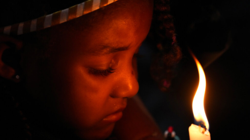 A girl holds her candle during a baptism ceremony in the chapel of the Kalunga quilombo, during the culmination of the week-long pilgrimage and celebration for the patron saint 