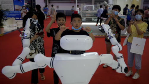 Children gesture as they play with a Chinese-made robot during the World Robot Conference at the Yichuang International Conference and Exhibition Centre in Beijing, Thursday, Aug. 18, 2022. (AP Photo/Andy Wong)