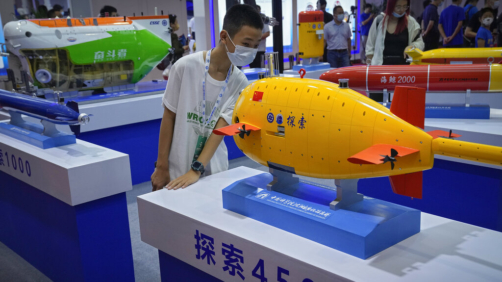 A child wearing a face mask takes a closer look at a Chinese-made unmanned submarines model on display at the World Robot Conference at the Yichuang International Conference and Exhibition Centre in Beijing, Thursday, Aug. 18, 2022. (AP Photo/Andy Wong)