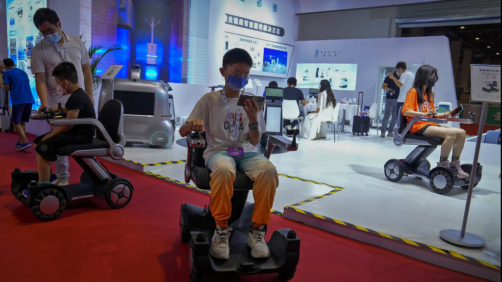 Children wearing face masks try out Chinese-made remote wheelchairs during the World Robot Conference at the Yichuang International Conference and Exhibition Centre in Beijing, Thursday, Aug. 18, 2022. (AP Photo/Andy Wong)
