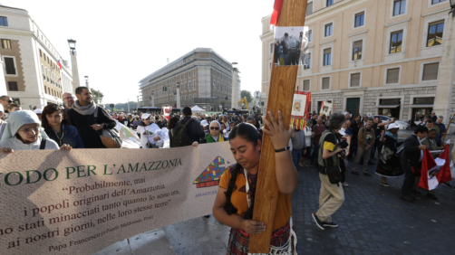 A woman carries a cross during a Via Crucis (Way of the Cross) procession of members of Amazon indigenous populations from St. Angelo Castle to the Vatican, Saturday Oct. 19, 2019. Pope Francis is holding a three-week meeting on preserving the rainforest and ministering to its native people as he fended off attacks from conservatives who are opposed to his ecological agenda. (AP Photo/Andrew Medichini)