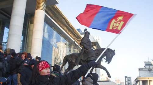 A protester waves a Mongolian national flag as protesters gather on the steps of the State Palace in Ulaanbaatar in Mongolia on Monday, Dec. 5, 2022. Protesters angered by allegations of corruption linked to Mongolia's coal trade with China have stormed the State Palace in the capital, demanding dismissals of officials involved in the scandal. (AP Photo/Alexander Nikolskiy)