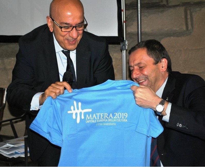 Anno 2012: Salvatore Adduce consegna al Ministro della Pubblica Istruzione Francesco Profumo la maglietta con il logo di Matera 2019 durante la candidatura della città. (Sito Facebook comune di Matera)